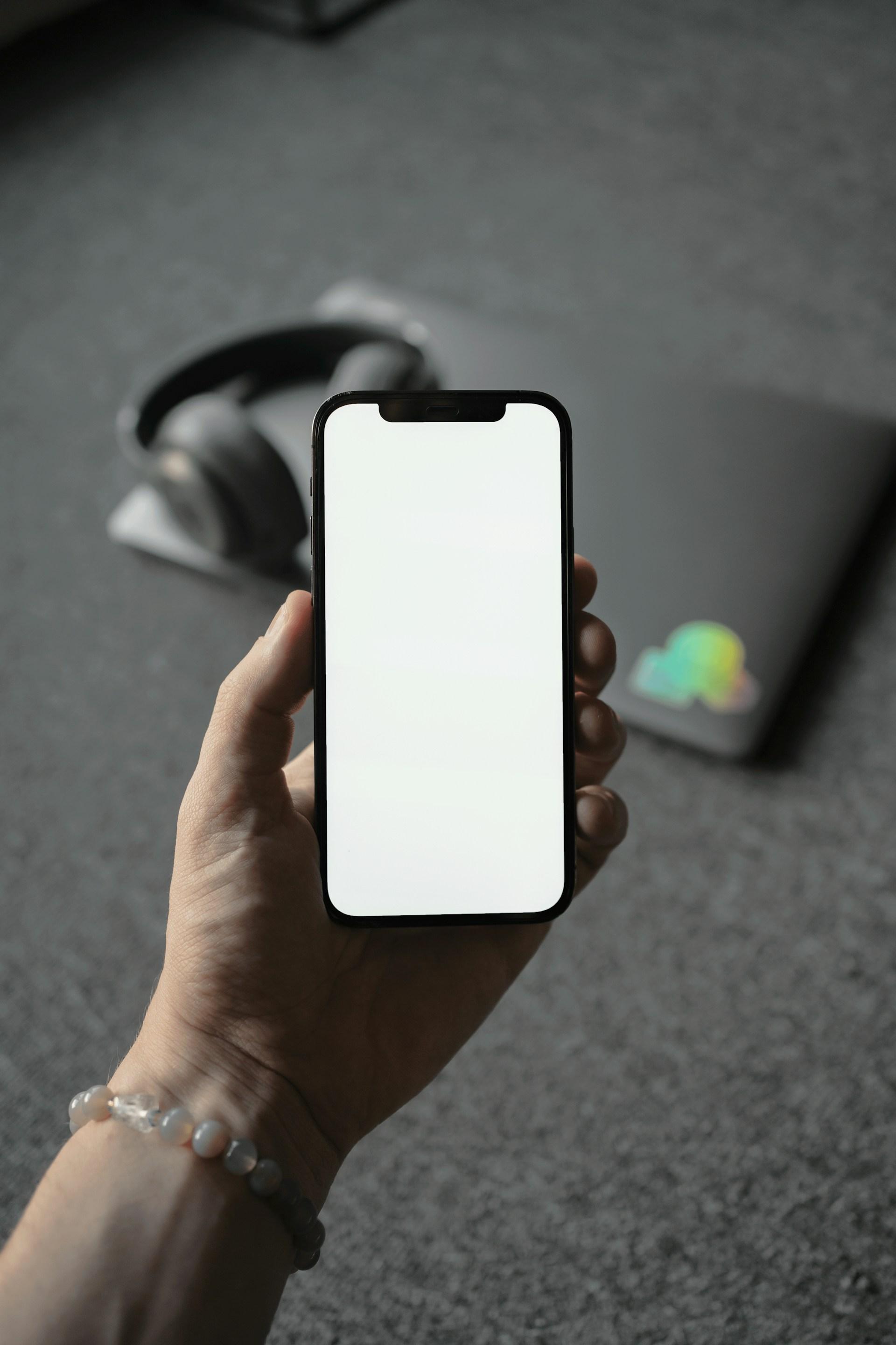 iPhone being held in hand with white screen